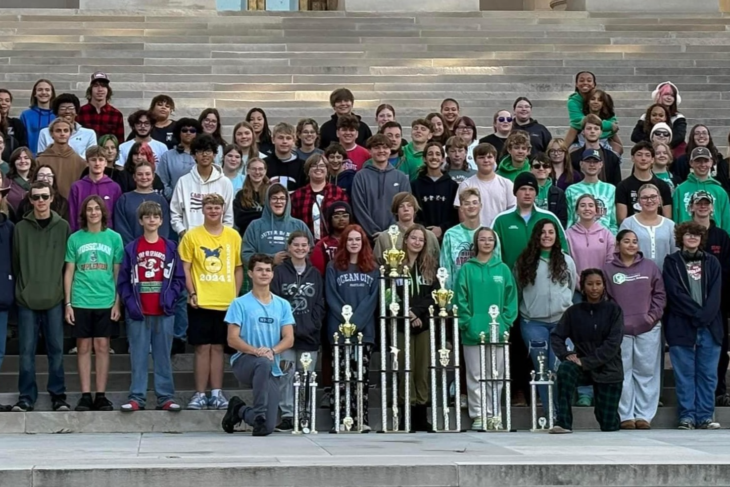 students with trophies in front of building