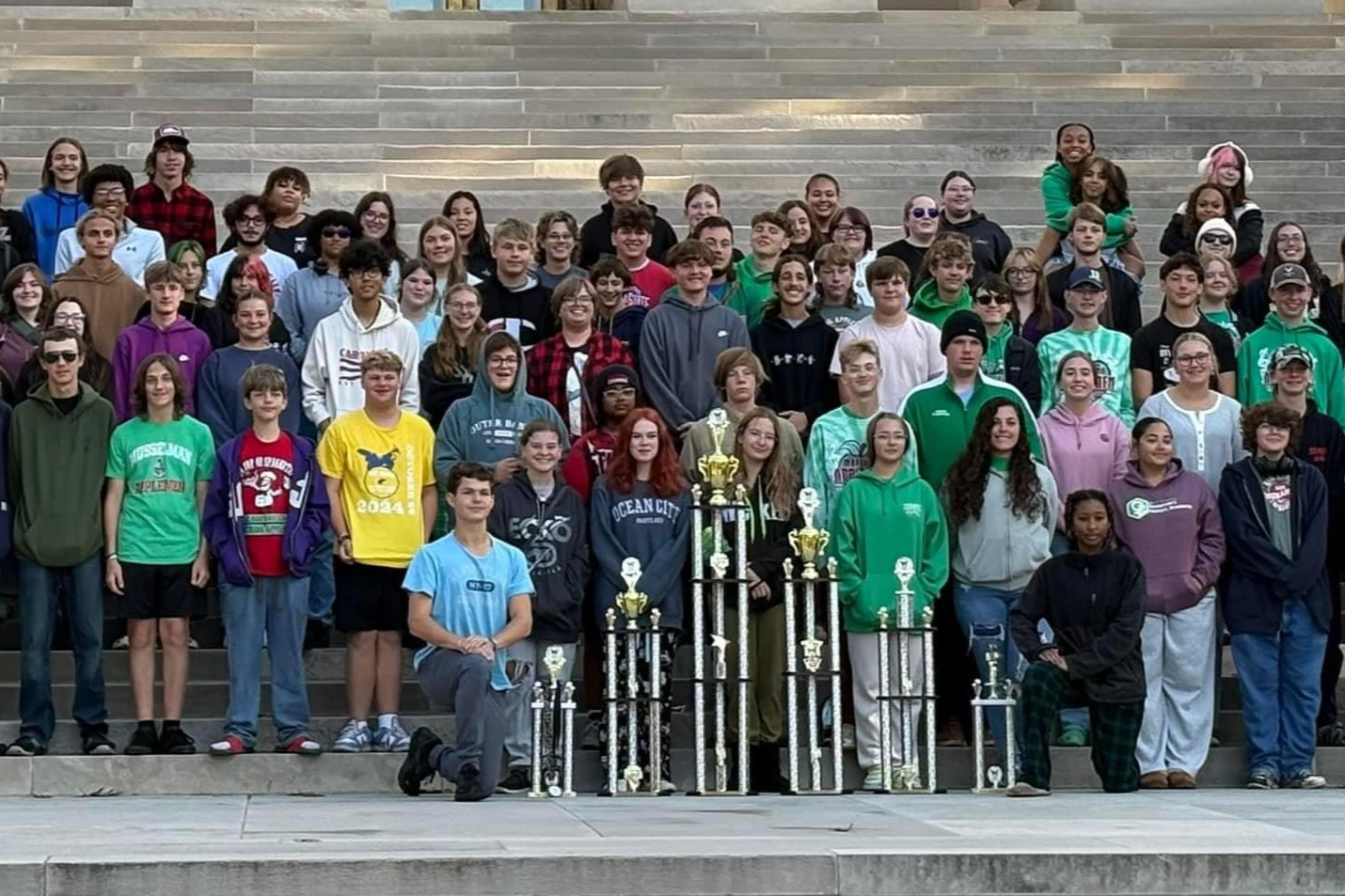 students with trophies in front of building