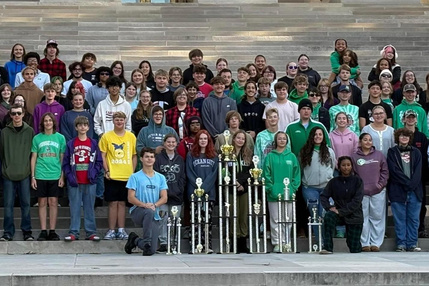 students with trophies in front of building