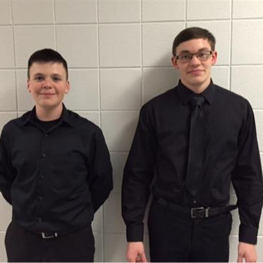 two students in black dress shirts one with no tie one with tie 