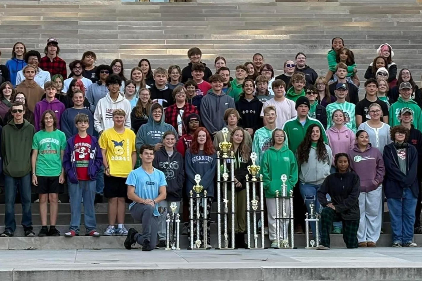 students with trophies in front of building