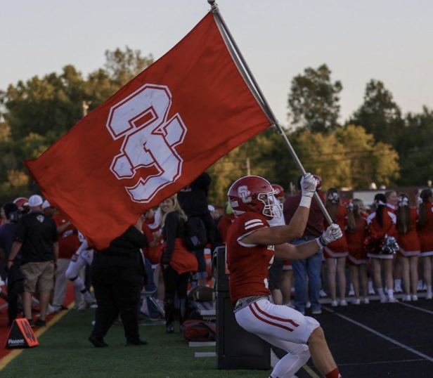 student athlete holding swartz creek flag