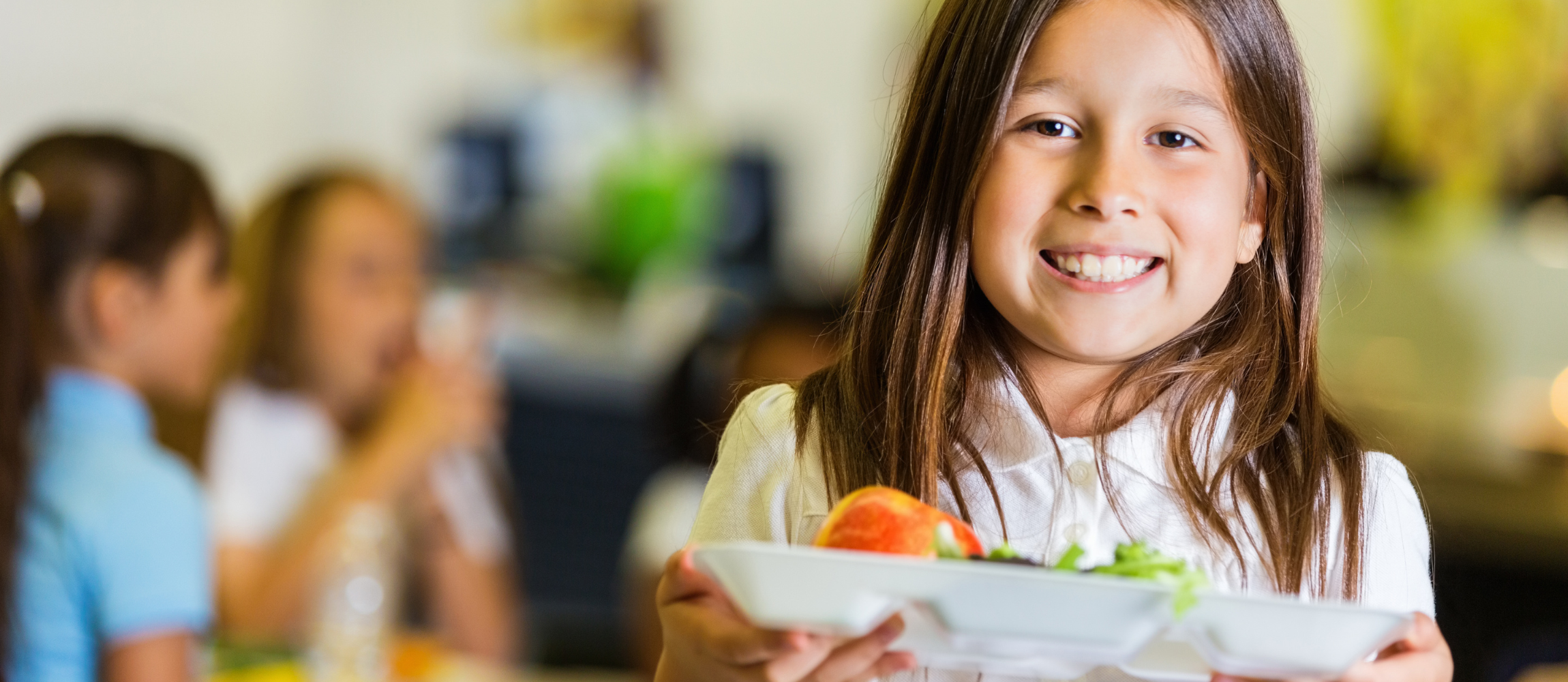 a child carries a tray of food in a cafeteria