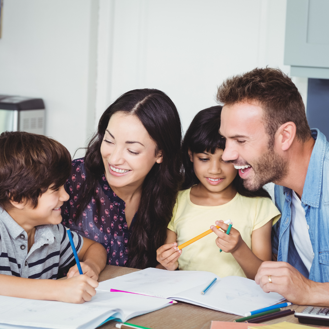 a woman and a man help two children with homework