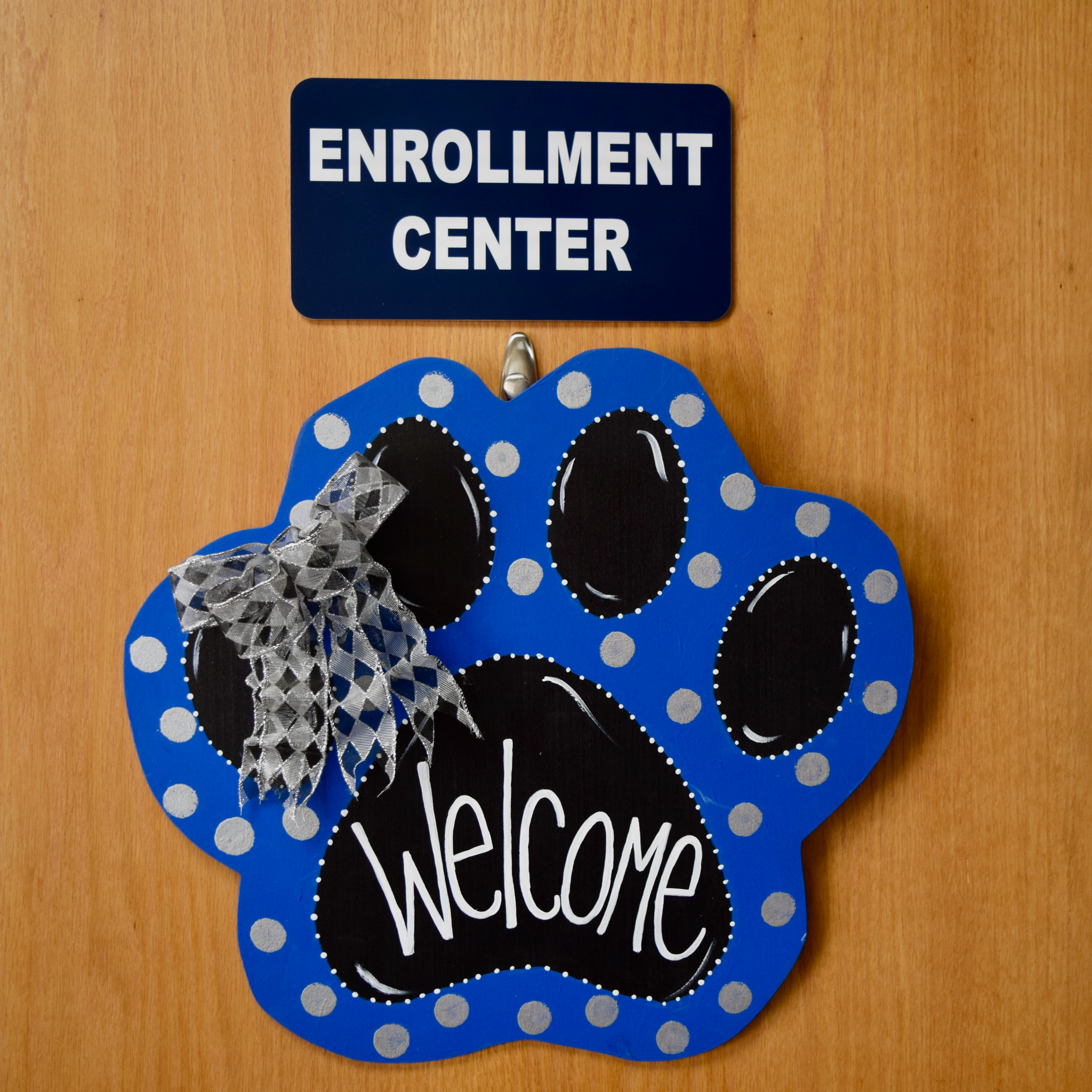 the words enrollment center above a blue wolf paw shaped sign that reads welcome