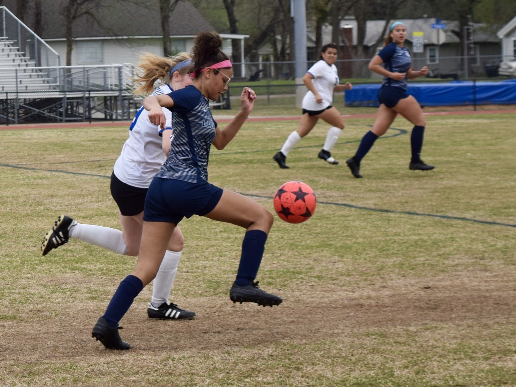 a girl kicks a soccer ball
