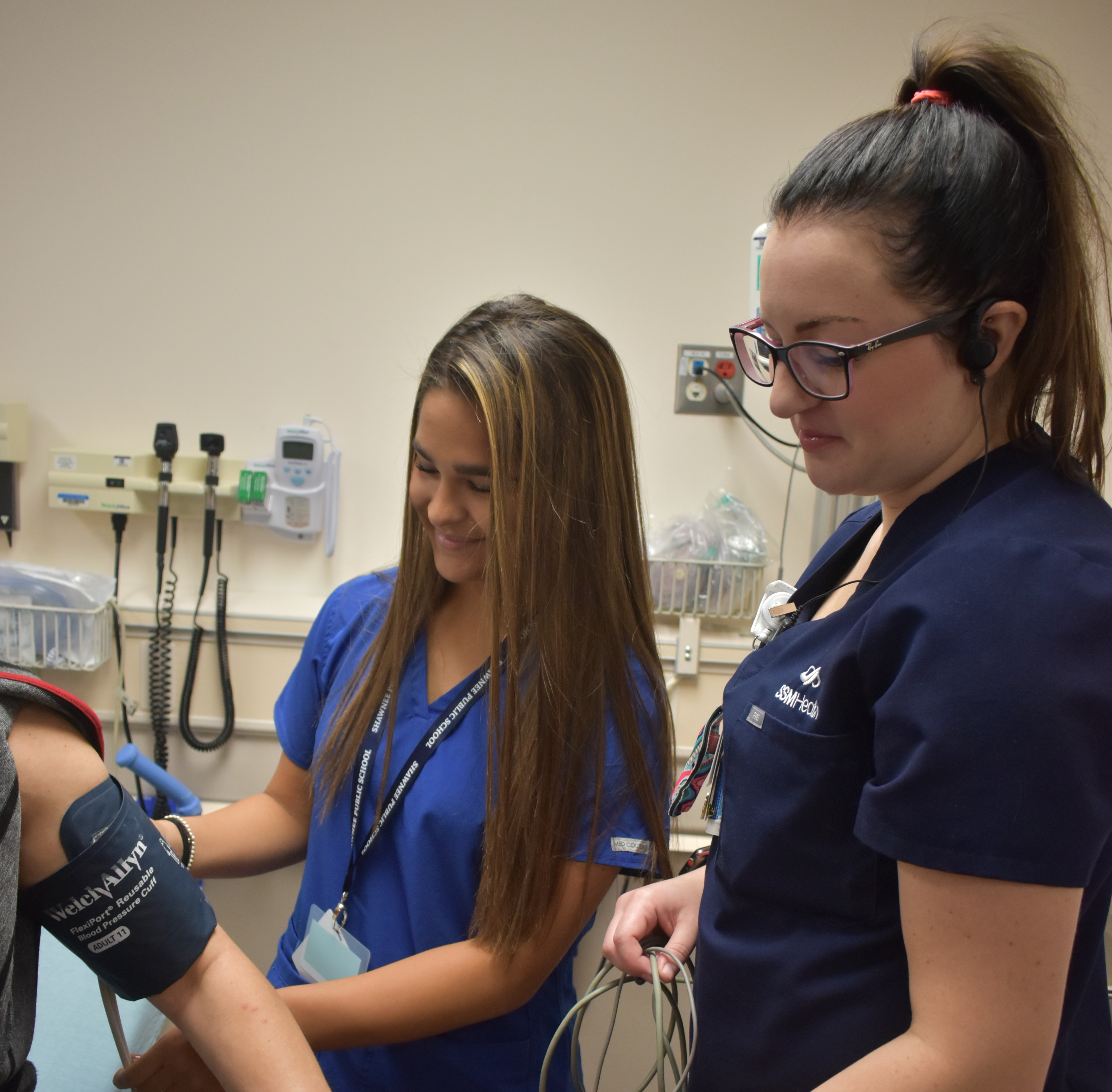 two women check someone's blood pressure with a cuff