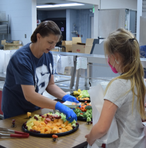 a cafeteria worker serves food to two students