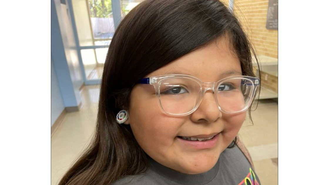 a girl wearing glasses smiles at the camera