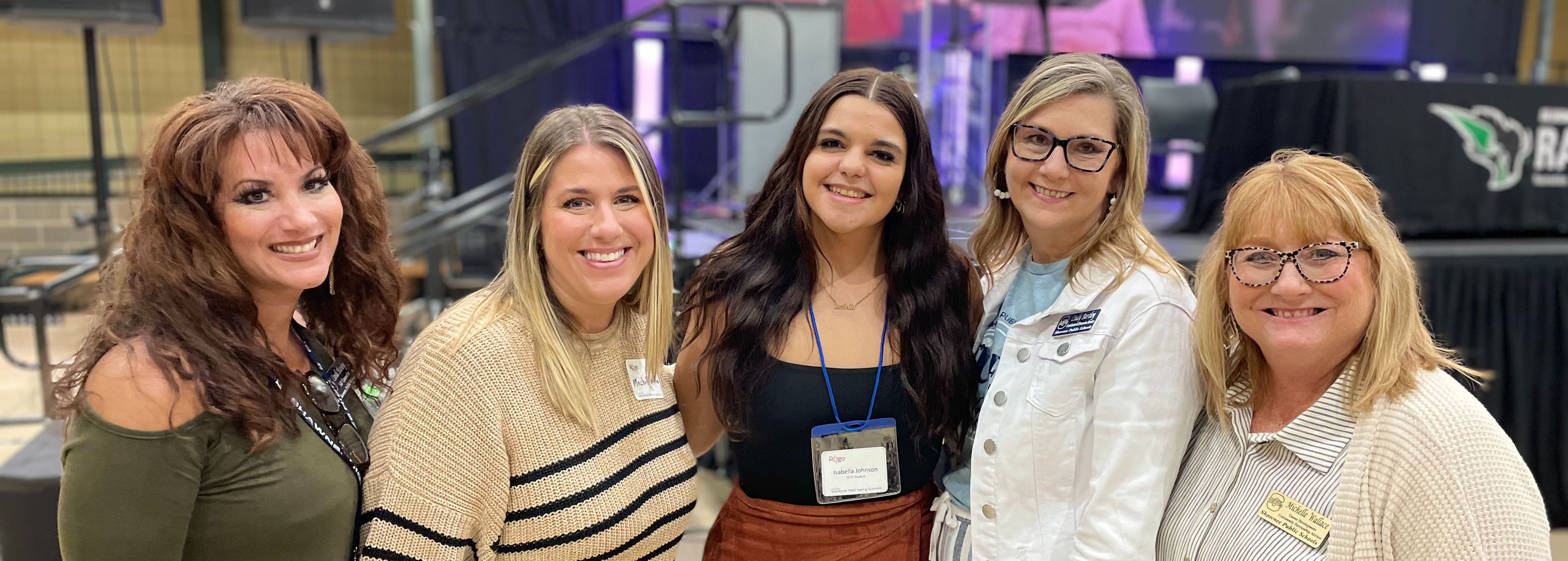 a high school student stands in between four women. all are smiling