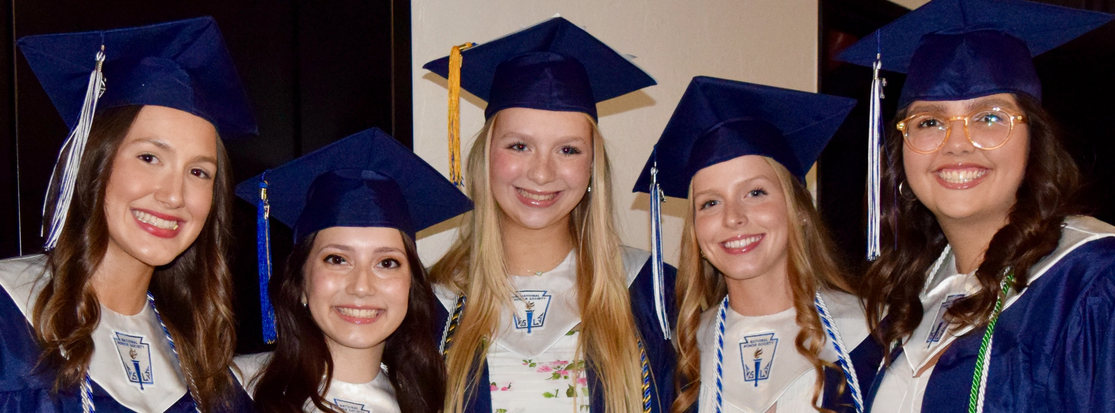 five girls wearing graduation regalia