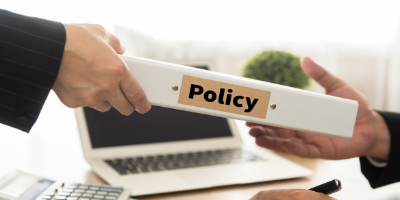 a hand holds a binder with policy written on the side