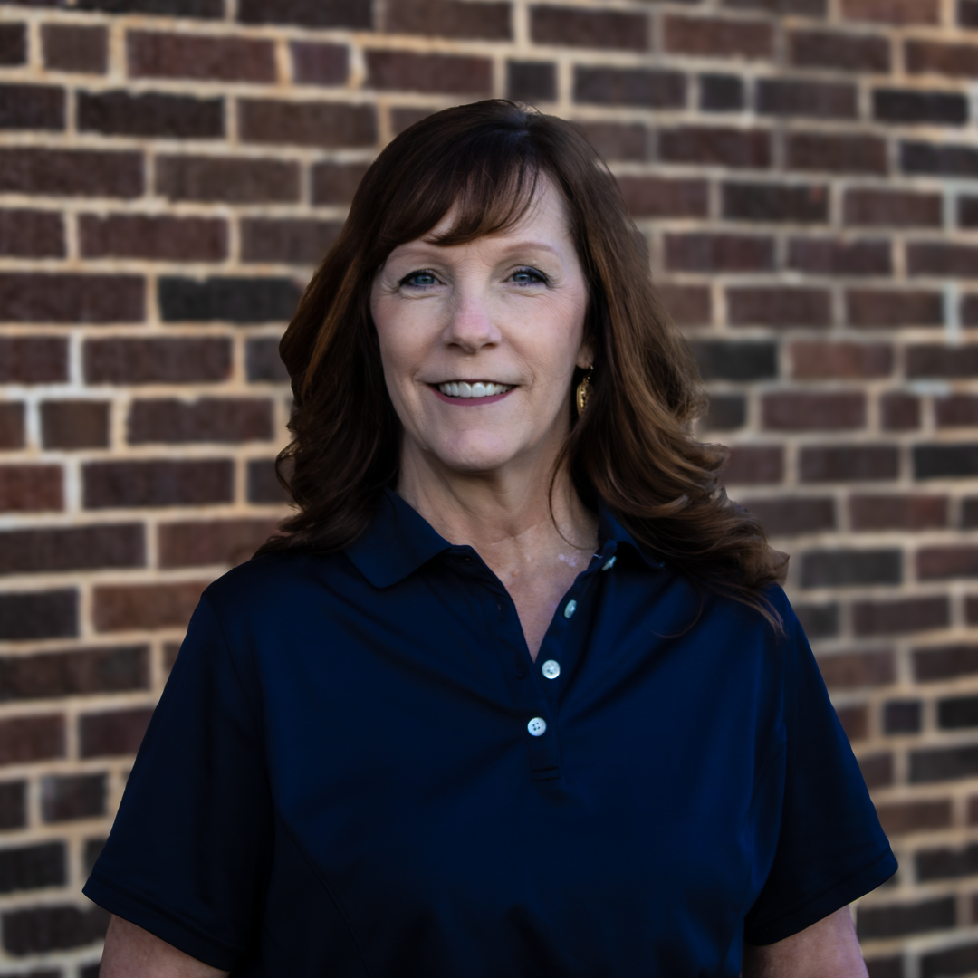 Woman in blue shirt in front of brick wall