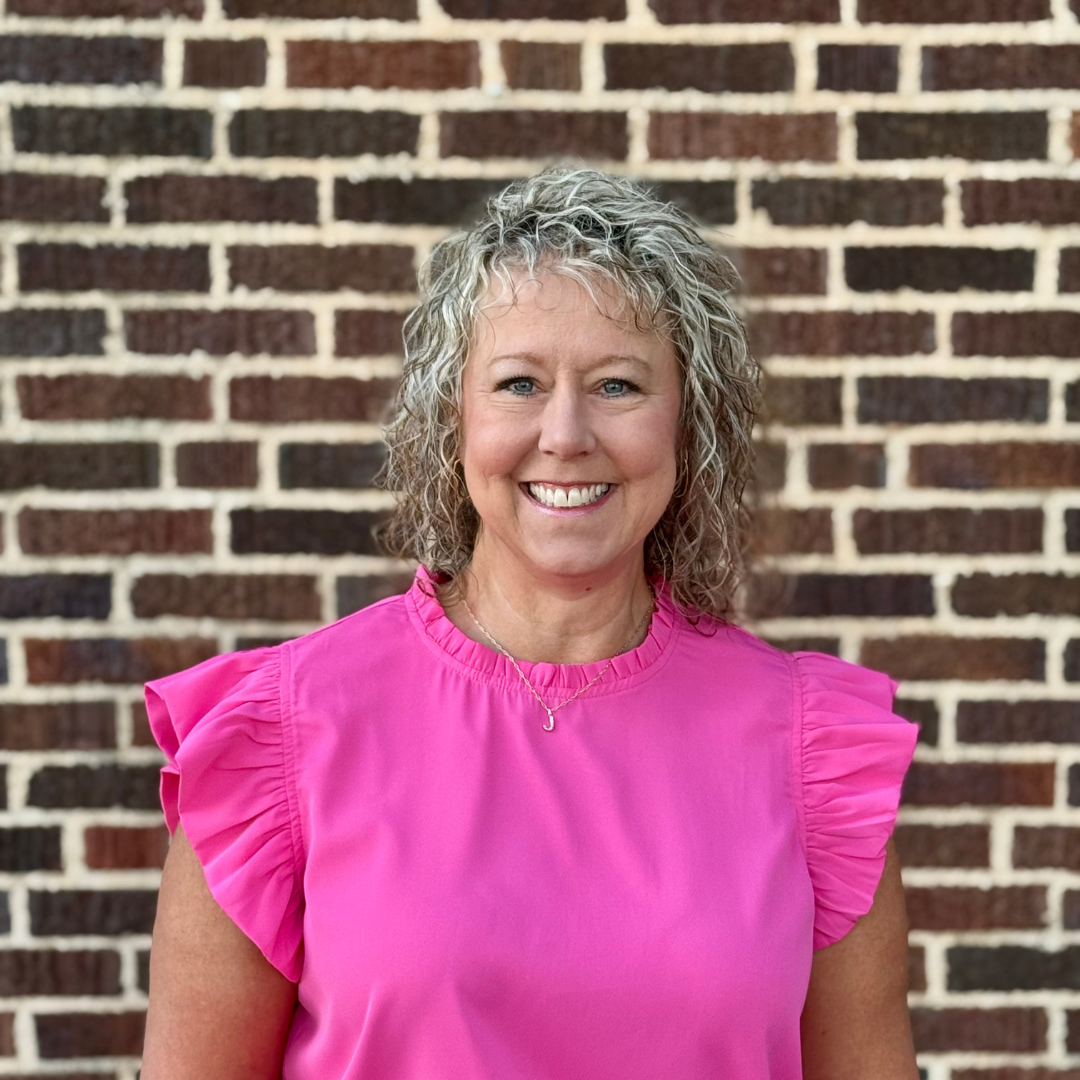 woman in pink shirt in front of brick wall