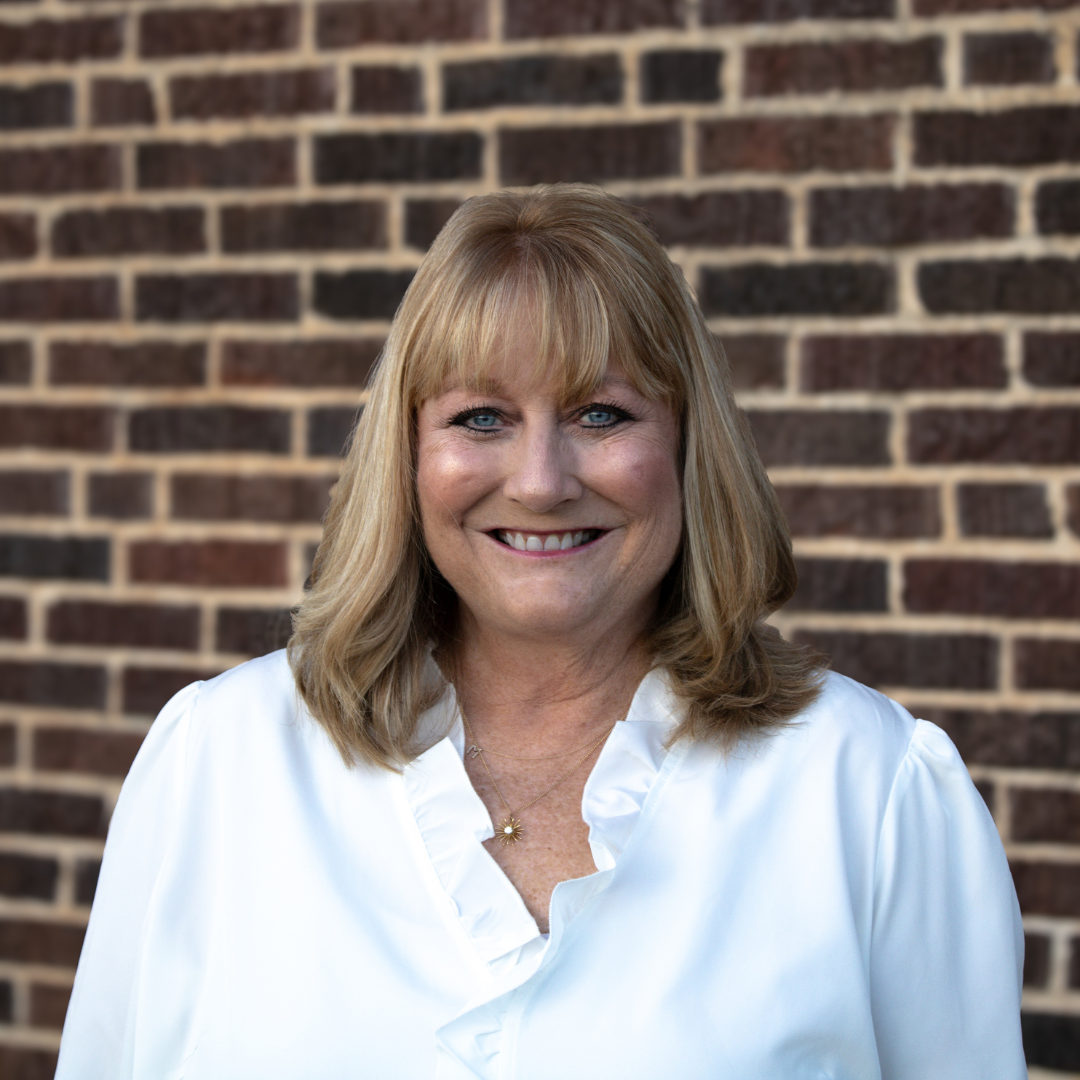 woman in white shirt in front of brick wall