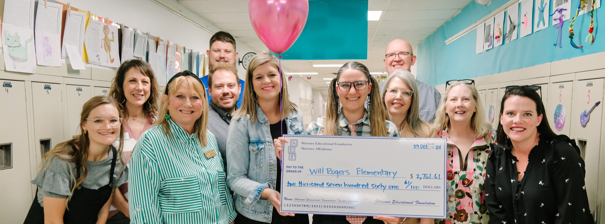 group of adults with balloons and large check