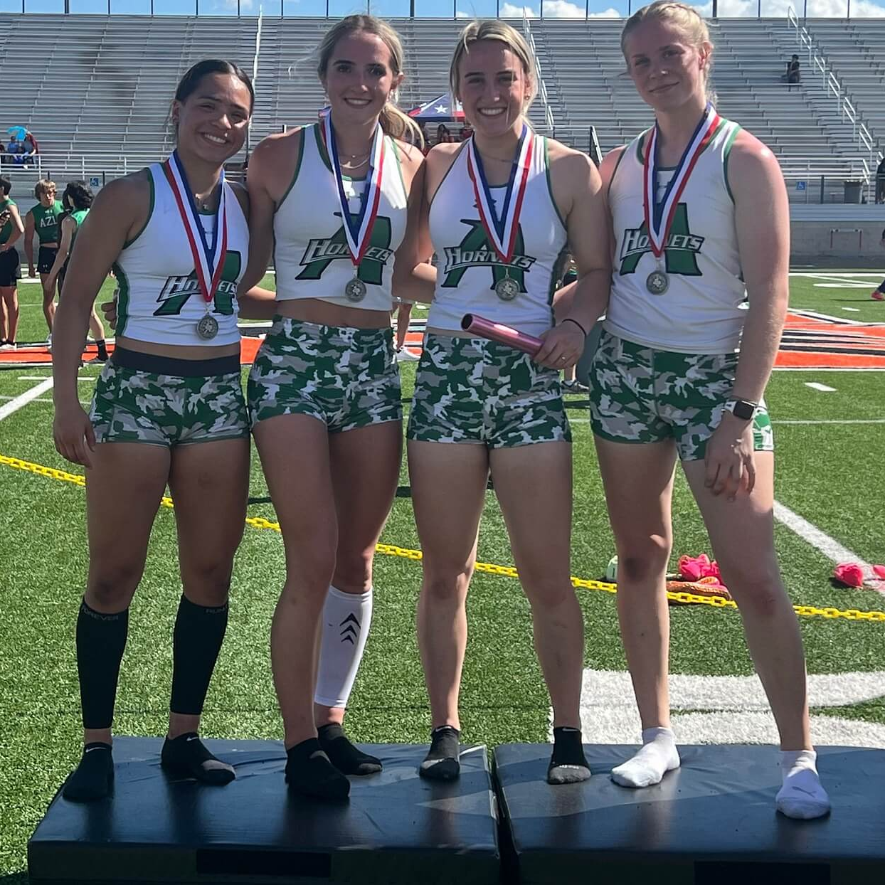 4 girls wearing track uniforms and medals