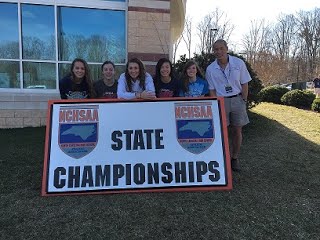 Swim team with state championships banner