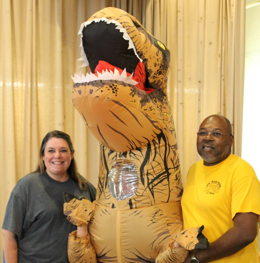 White woman and Black man with a fake dinosaur