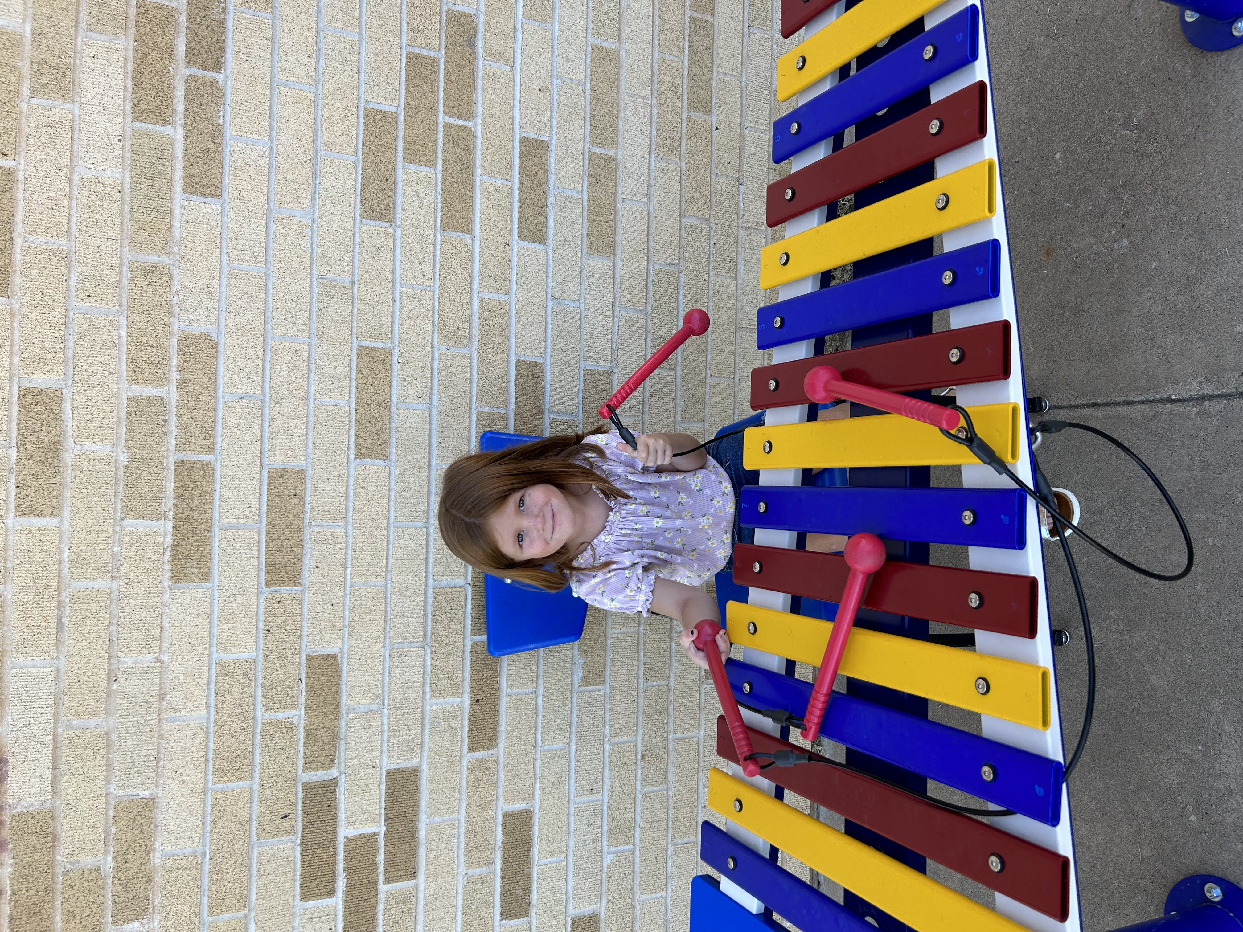 a girl sits behind a colorful xylophone