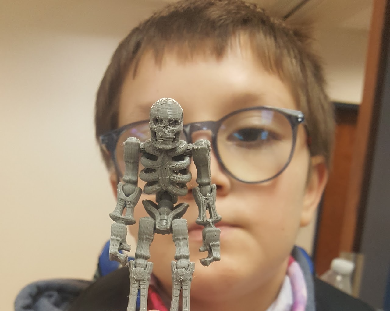 a boy looks at a model of a skeleton