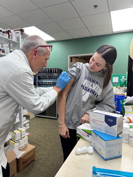 a man in a white coat prepares to give a vaccine to a woman