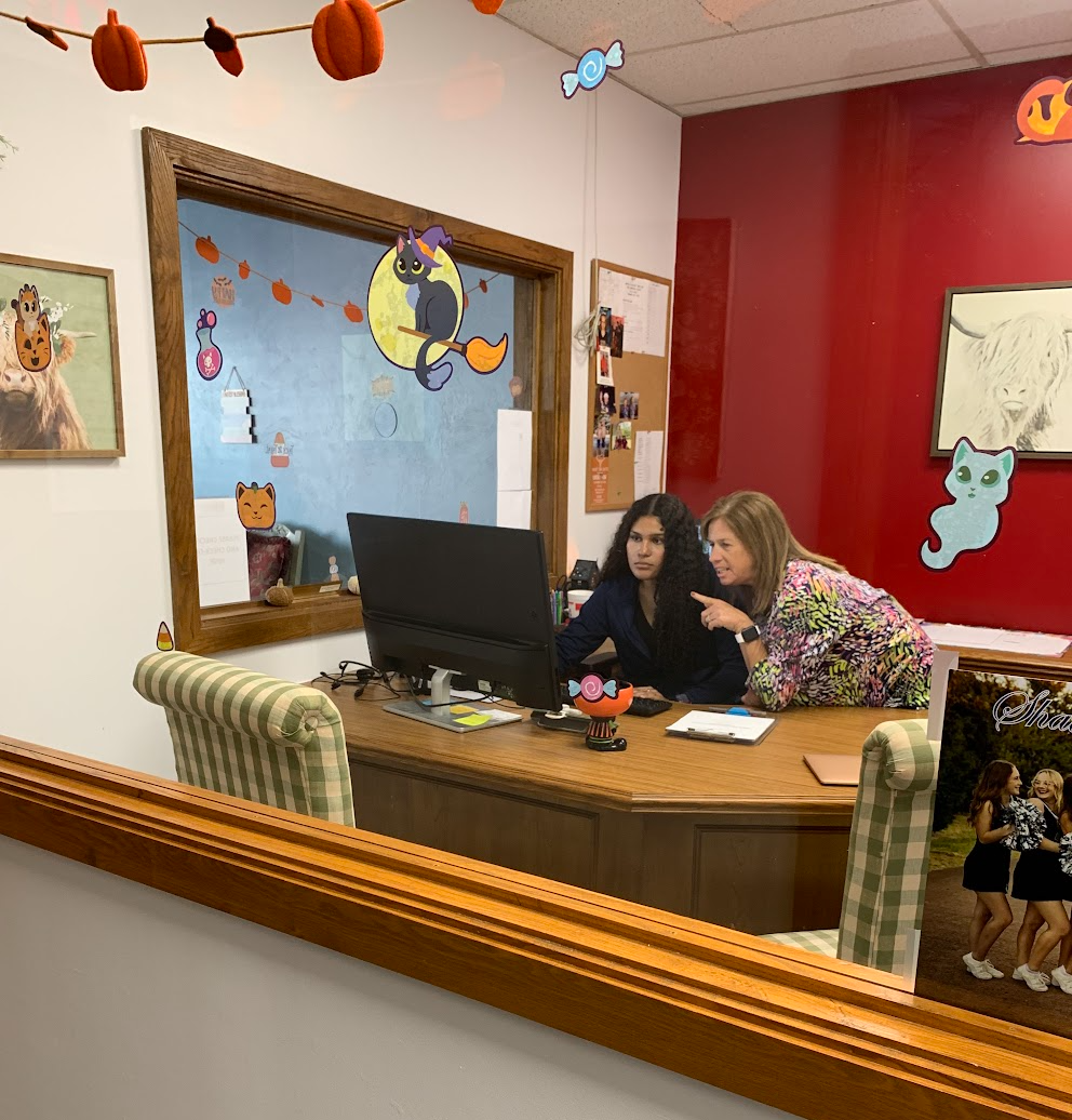 two women sit behind a computer