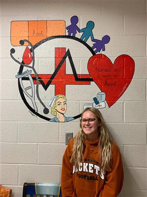 student standing in front of medical mural