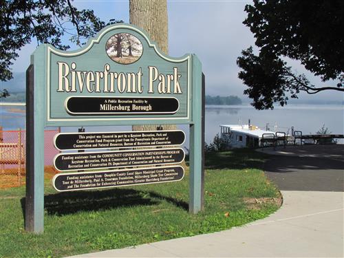 Riverfront with sign and ferry boat