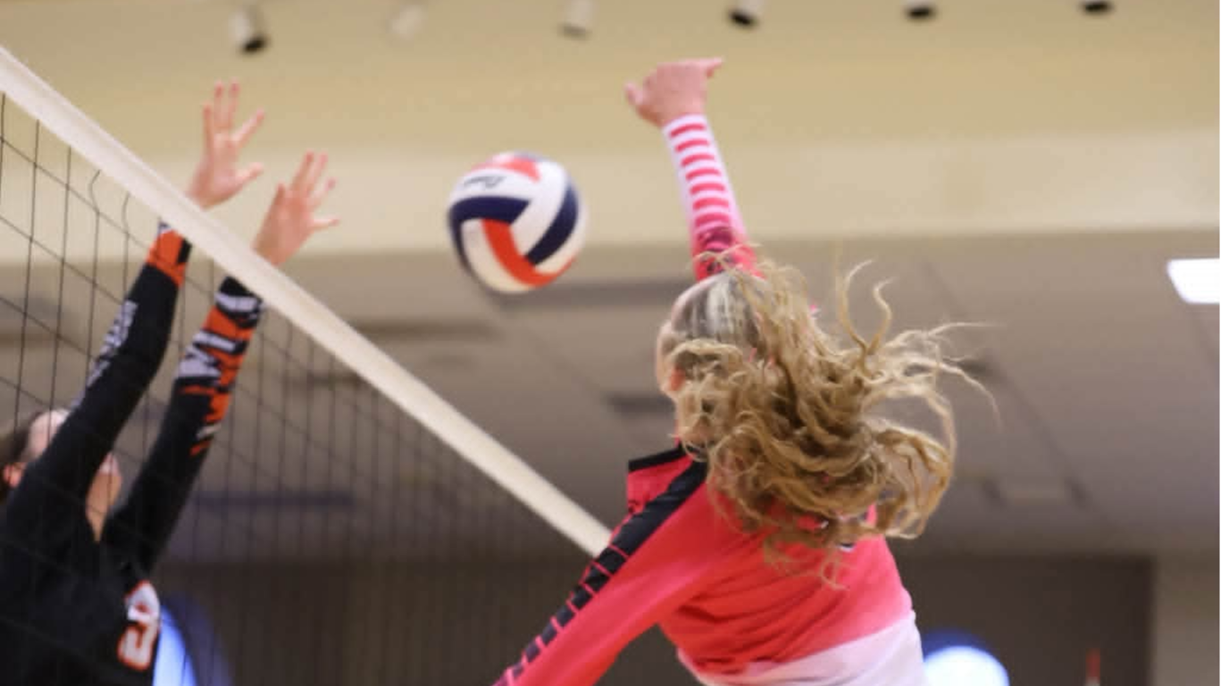 female volleyball player spikes ball