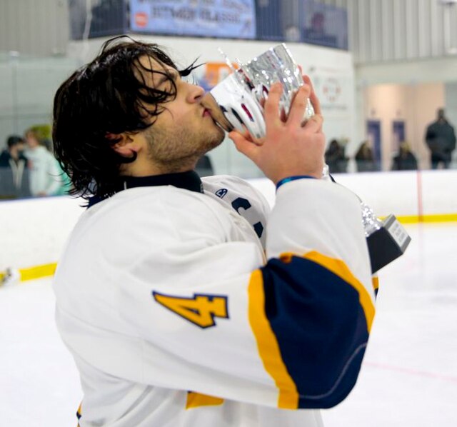 Ramsey Ice Hockey player celebrates with the trophy. 