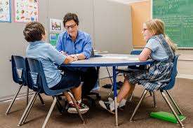 teacher sitting at u-shaped table with 2 students