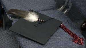 graduation cap on chair with feather on it