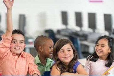 4 students sitting in a classroom, one raising his hand