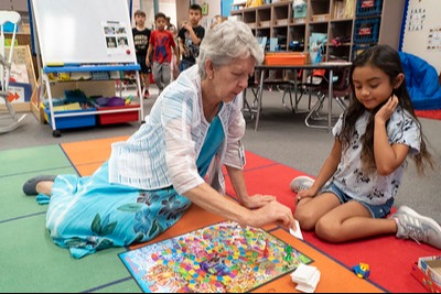 substitute teacher sitting on the floor  doing a puzzle with a student