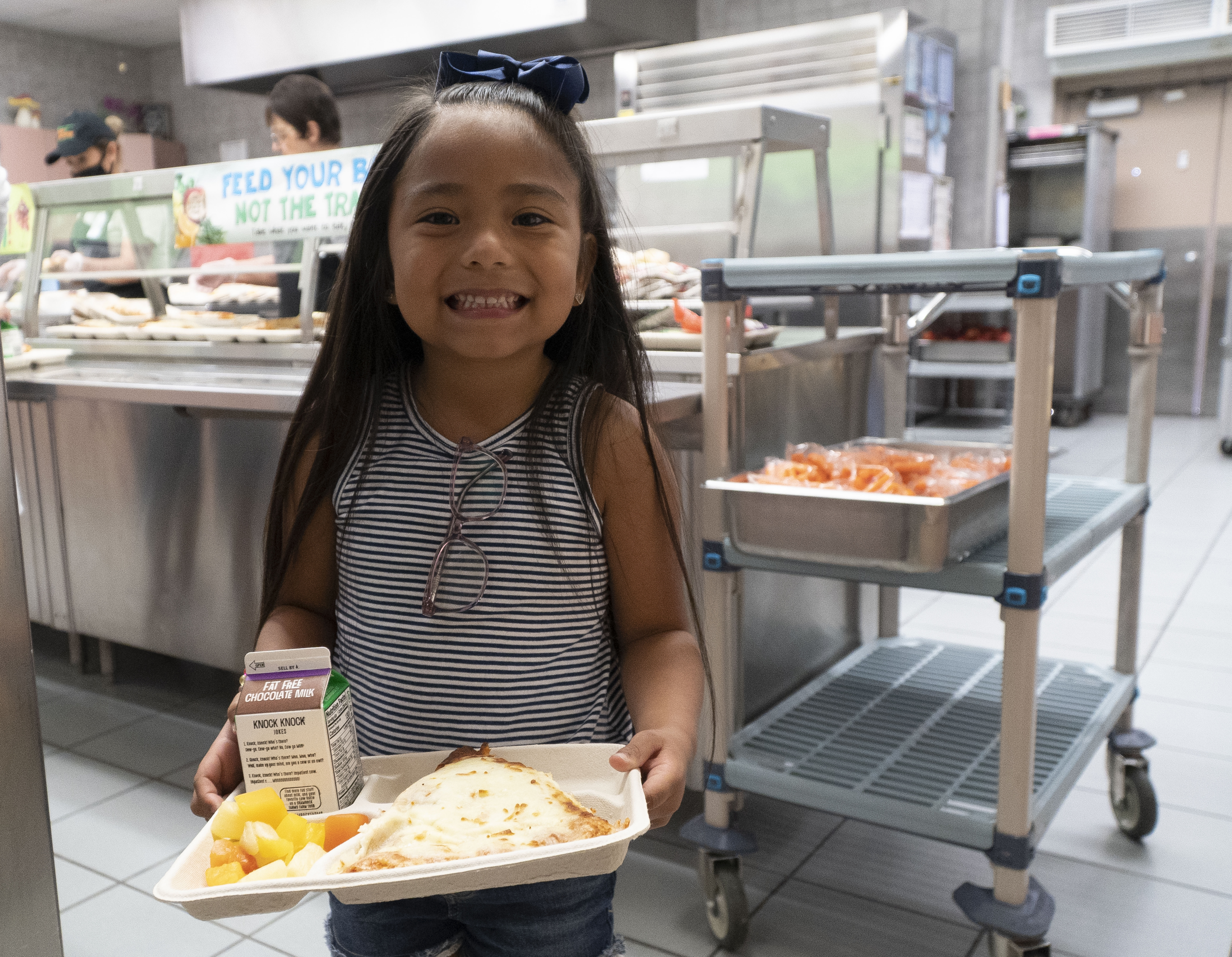 student with a tray of pizza in the school cafeteria