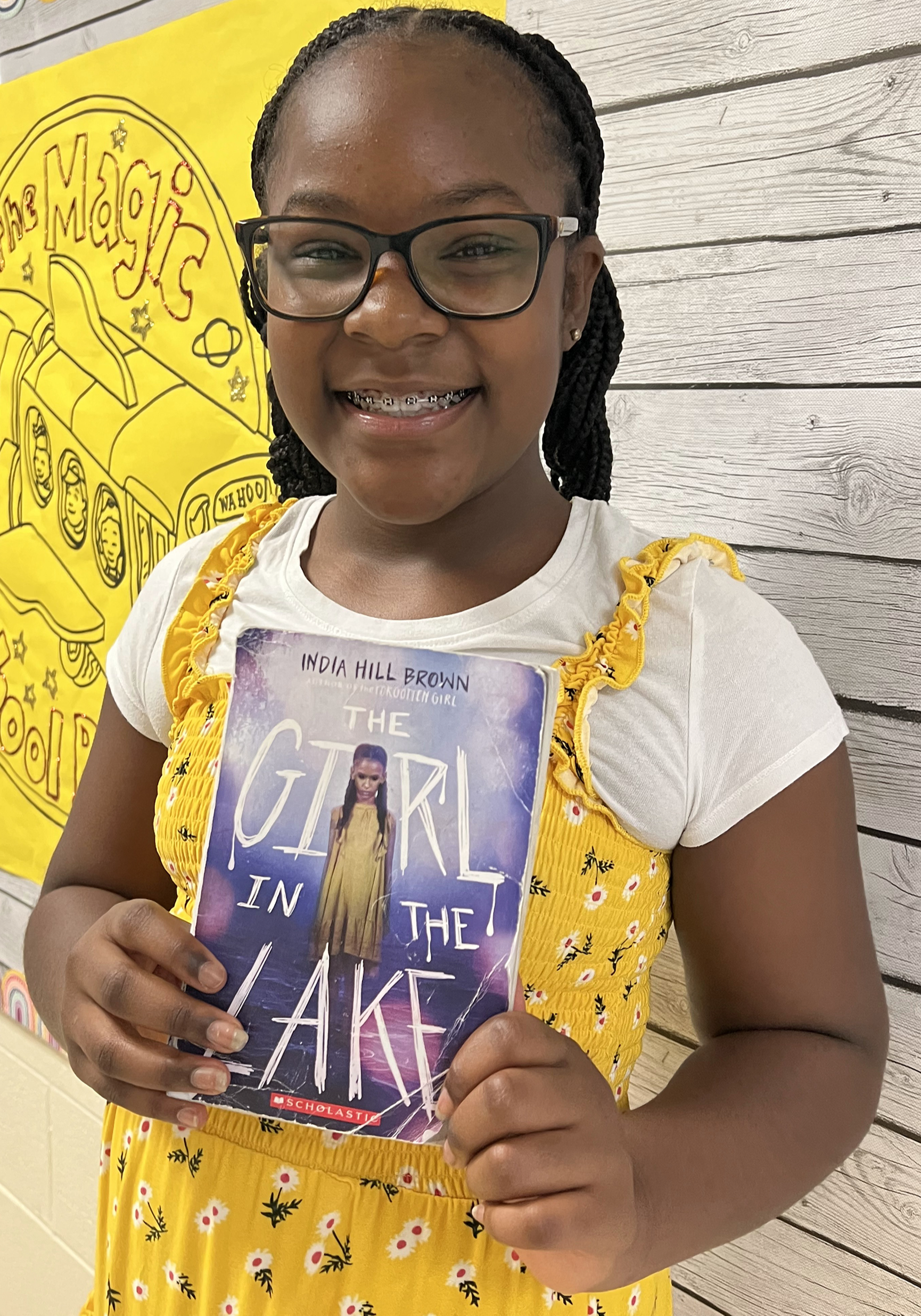 Female student holding up her book and smiling