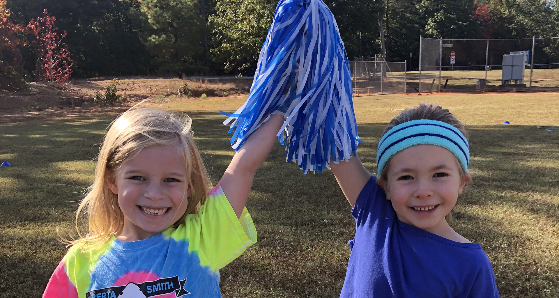 Two girls holding up a pom pom with their hands together in victory.