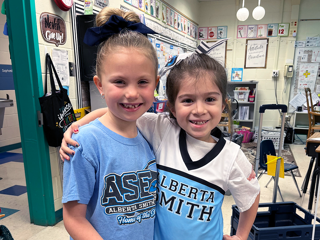 Two female students wearing their school spirit wear pose for a photo.