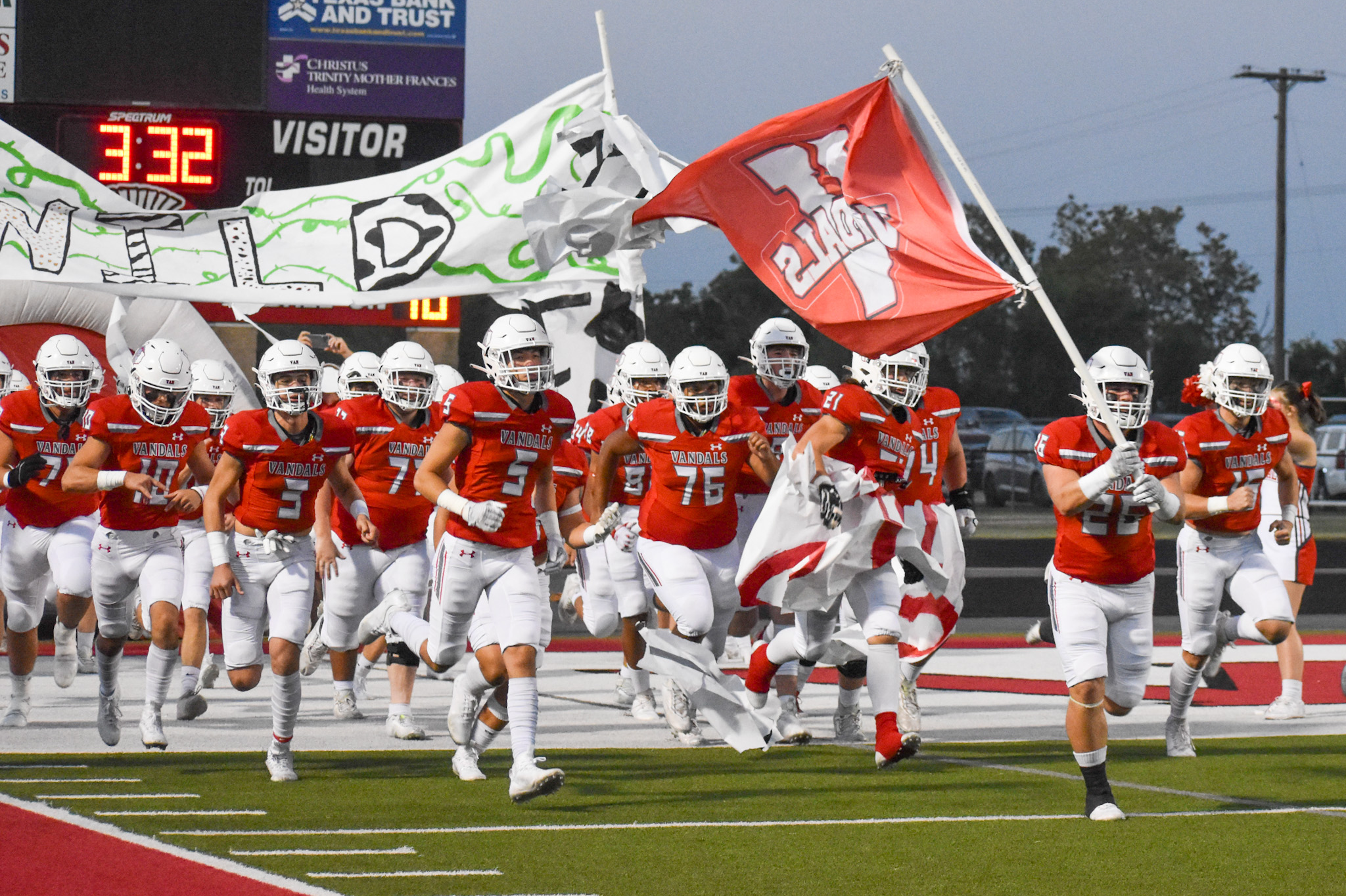 the van vandal football team run out onto the field carrying the vandal flag