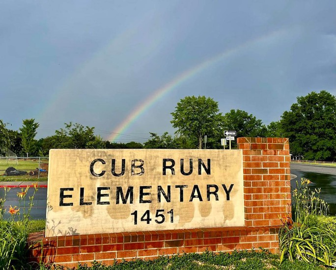 Sign that says, Cub Run Elementary 1451, with rainbow in the sky behind it.