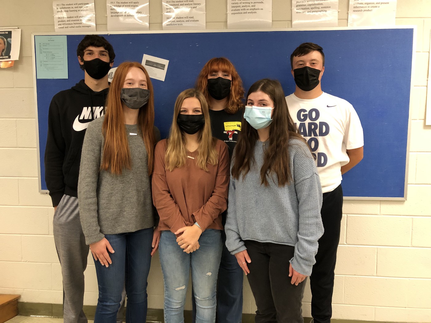 6 students standing in front of bulletin board