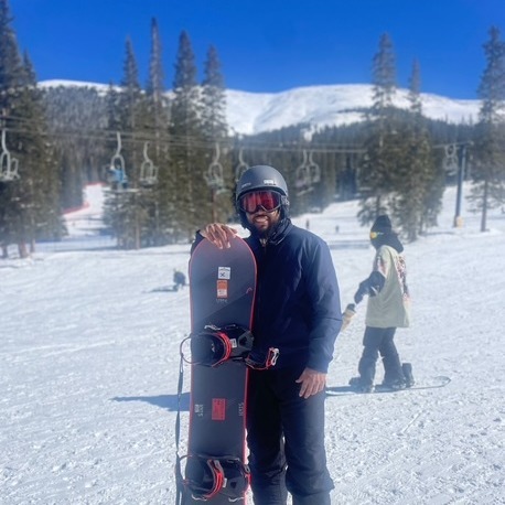 Picture of Coach Alpough in the snow holding a snowboard