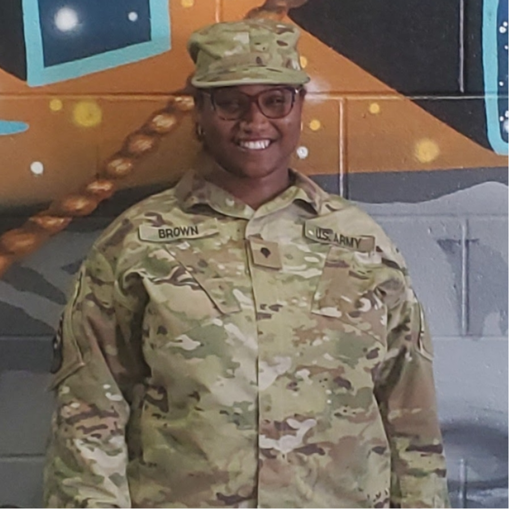 SGT Brown in uniform standing in from of a wall smiling