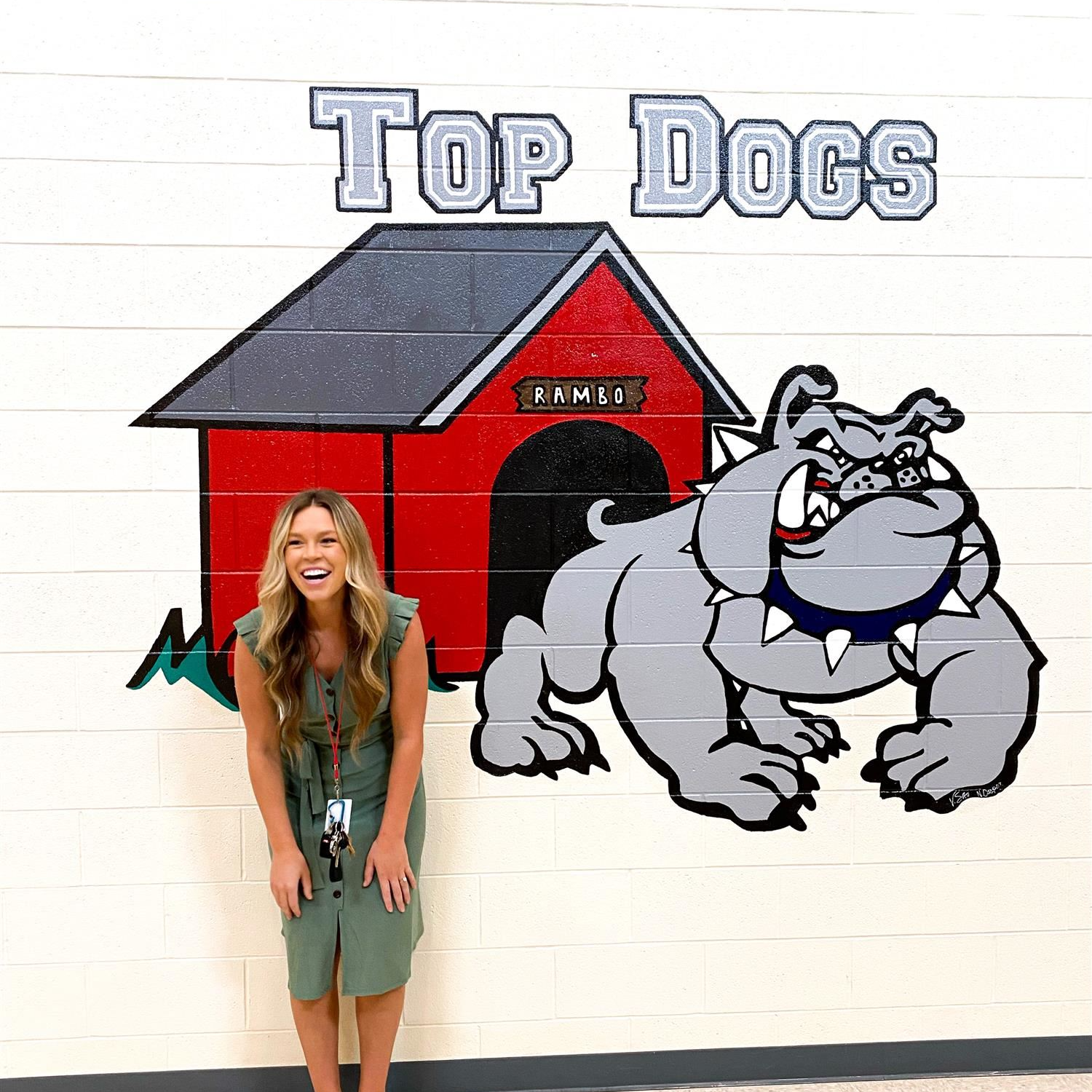 Malea Hall smiling off guard in front of the "Top Dog" mural on campus
