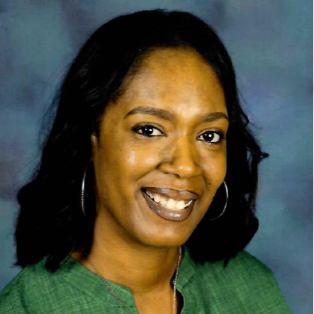 Dawnitra Williams smiling in front of white board wearing a black shirt