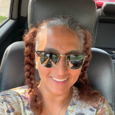 Picture of Miriam Pena in her truck, wearing sunglasses with two pigtails in braids.