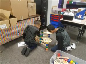 2 students work together to build and test a wooden marble run 
