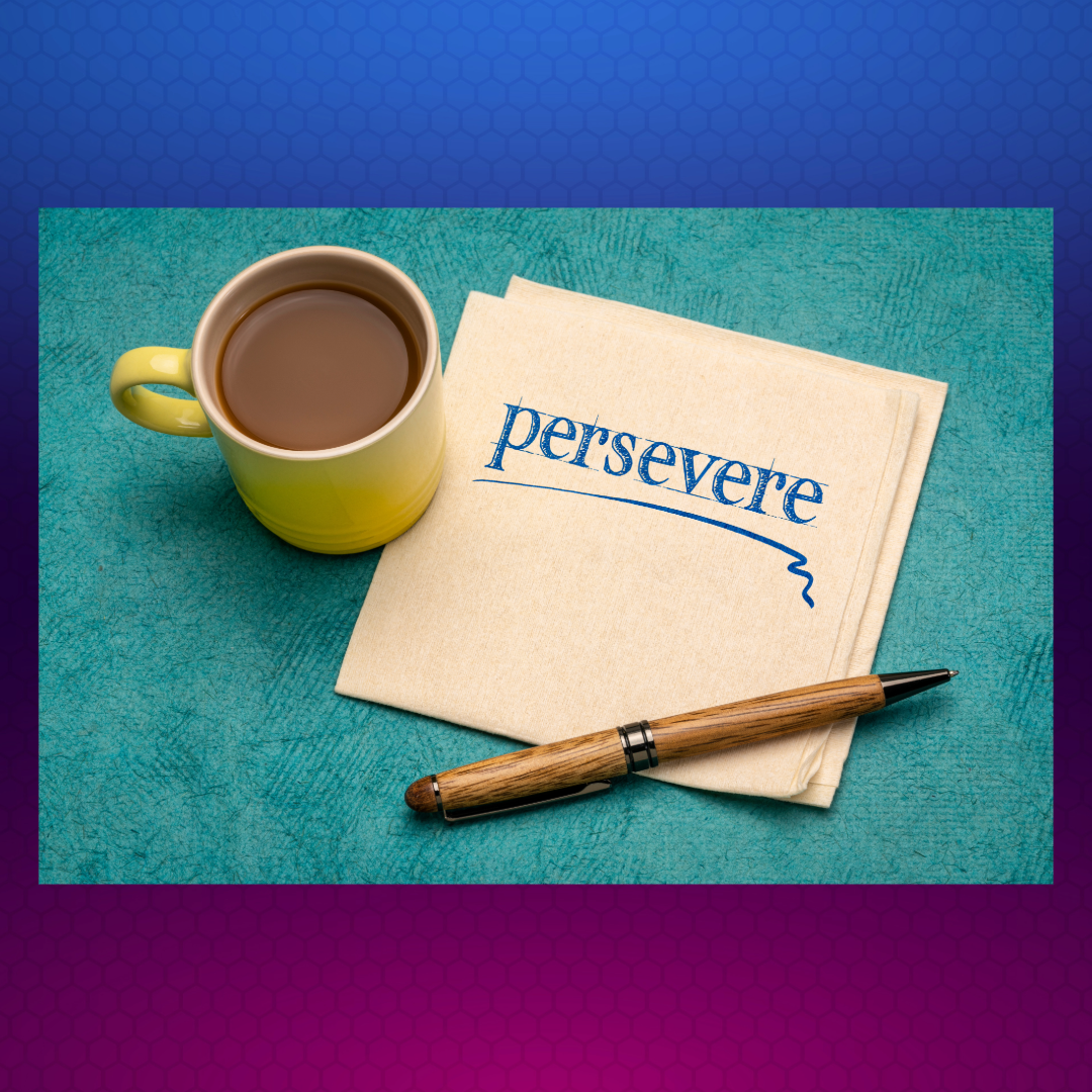 A coffee mug and a wooden pen sit near a note that reads- persevere