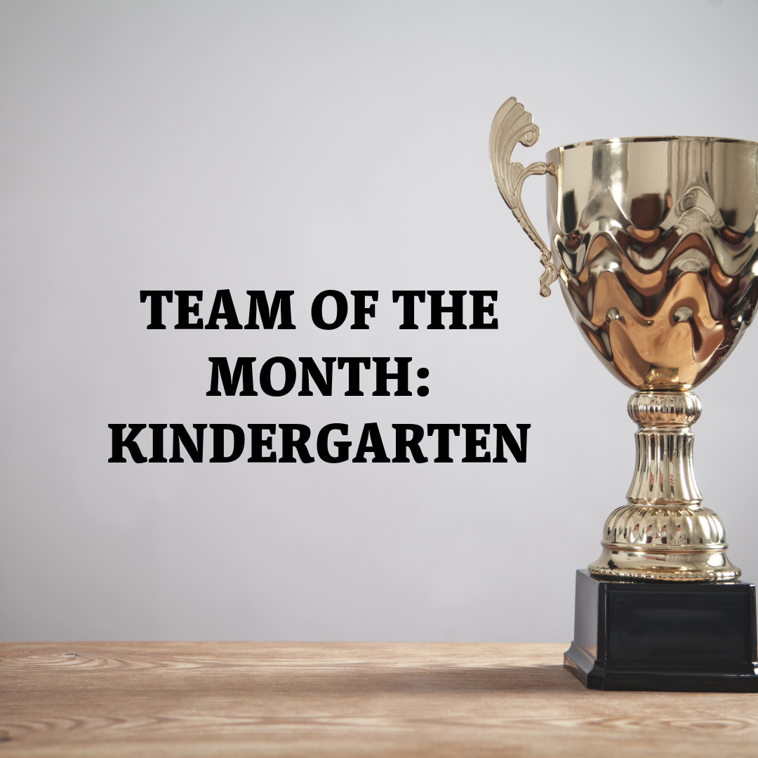 A trophy sits against a pale gray background. Black lettering on the left reads:  TEAM OF THE MONTH: KINDERGARTEN